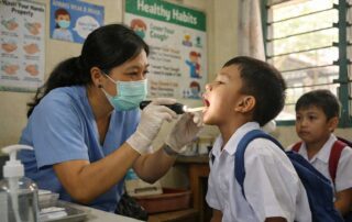 School nurse checking a child's throat during a health screening as the Department of Health monitors rising herpangina and enterovirus cases in Philippine schools
